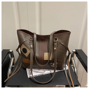Detail of dark brown PU leather tote bag with vintage patches and metal rivets detail