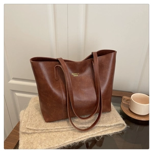 Détail du cabas en cuir PU marron caramel avec lettrage doré sur une couverture en tricot