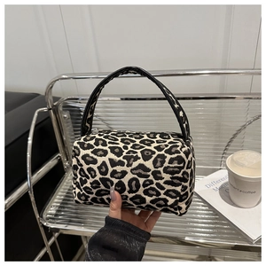 Detail shot of leopard print fabric texture and black handles on mini pillow bag