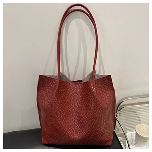 Detail of dark red tote bag with woven embossing pattern and long slender shoulder straps
