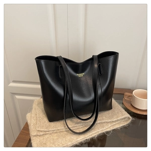 Détail de la texture en similicuir noir brillant du sac cabas avec lettrage doré
