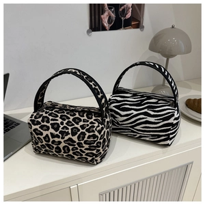 Detail of leopard and zebra pattern mini pillow bags with black handles on desk