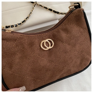 Detail of brown suede underarm bag with quilted pattern and golden chain strap