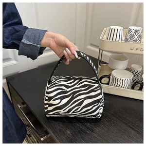 Detailed close-up of a zebra pattern handbag with a smooth round handle and zipper top