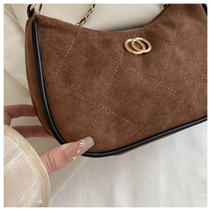 Close-up of brown suede underarm bag with diamond stitching and gold ring buckle