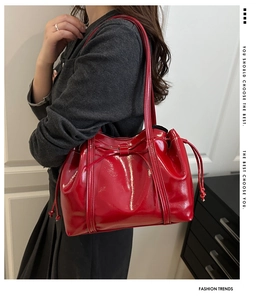 Detail of red patent leather tote bag with bow accent and glossy mirror finish texture
