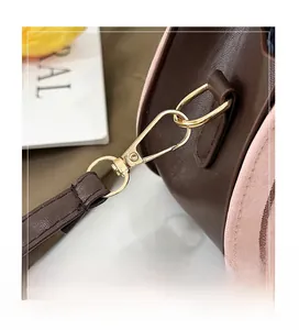 Detail of metal hook and gold D-ring on pink and brown leather crossbody bag