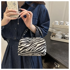 Close-up of stylish zebra-pattern handbag with black handles and high-quality woven fabric