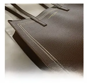Close-up of deep brown lychee leather tote bag with decorative white stitching details