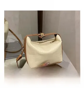 Close-up of cream textured shoulder bag featuring brown contrast straps and gold hardware