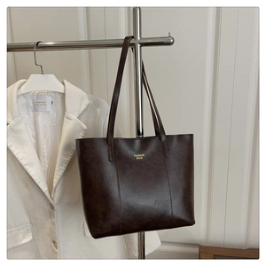 Détail d'un sac cabas en cuir marron foncé avec inscription dorée Fashion Bags sur le devant
