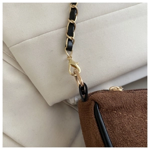 Detail of brown suede shoulder bag with gold chain strap and elegant metal hardware