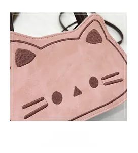 Close-up of pink suede cat crossbody bag featuring brown embroidered facial details
