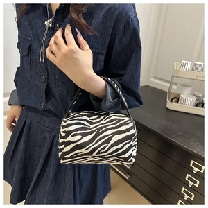 Detail shot of a zebra stripe pattern mini handbag with black handle and woven texture