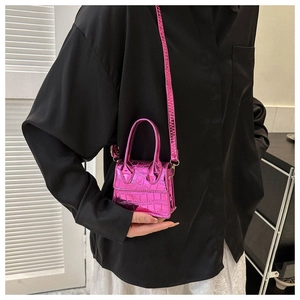 Detail of pink croc-effect micro bag shown with black shirt and white skirt outfit