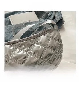 Close-up of silver quilted crossbody bag with metallic finish and woven strap