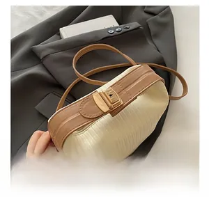 Detail view of premium golden hardware and brown leather strap on textured cream bag