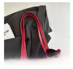 Detail of red glossy tote bag featuring slim handles and shiny faux leather texture