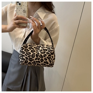 Detail of leopard jacquard cylinder handbag with black curved handles and fabric texture