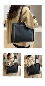 Detail of black lychee grain leather tote bag with gold lettering and metal rivets