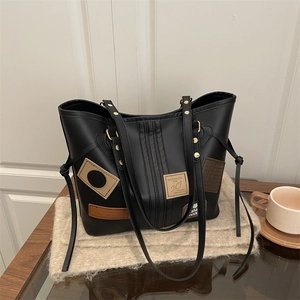 Chic black faux leather tote bag with colorful letter patches and golden stud details