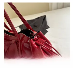 Close-up of red patent leather tote bag showing glossy texture and drawstring detail