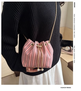 Pink woven bucket bag with elegant pearl drawstring and golden chain strap detail