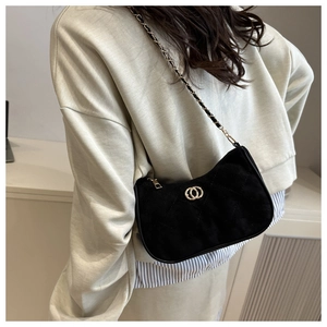 Detail of black suede shoulder bag featuring gold double-ring logo and quilted texture