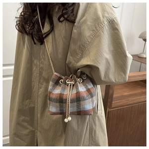 Dettaglio borsa a secchiello vintage in lana scozzese con coulisse di perle e catena