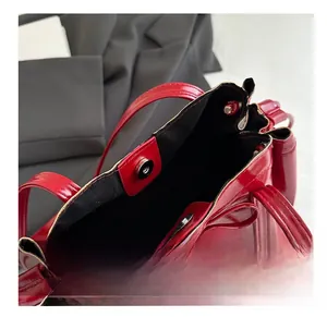 Detail view of red glossy dumpling bag featuring a secure magnetic metal buckle closure