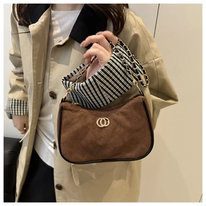Detail of a brown suede hobo bag with a gold metal clasp and striped fabric lining