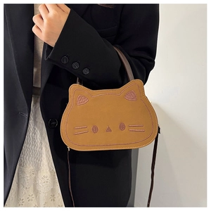 Detail of a brown cat-shaped crossbody bag with pink embroidered feline features