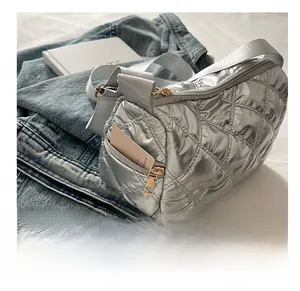Detail view of the side zipper pocket on silver quilted barrel bag for storing cards