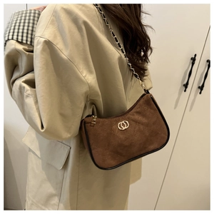 Detail view of brown suede underarm bag with gold logo and black leather trim
