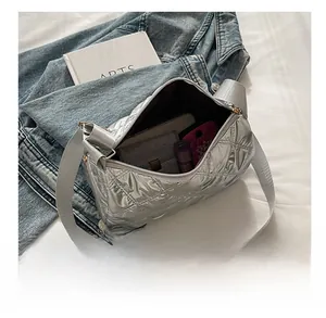 Detail view of the spacious inner storage of the silver quilted crossbody bag