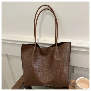 Detailed close-up of dark brown woven leather tote bag with large capacity in interior setting