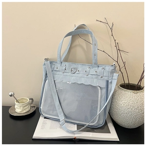 Detail view of light blue ita bag with heart-shaped metal clasp and clear display window