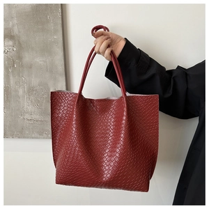 Close-up of deep red tote bag featuring crocodile pattern embossing and long handles