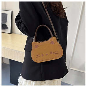 Detail of brown cat-shaped crossbody bag featuring cute face embroidery and soft texture