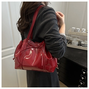 Detail of red patent leather tote bag with bow accent and side drawstring design