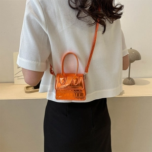 Mini orange crocodile texture handbag with top handle and crossbody strap on model back