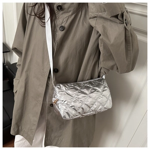 Silver quilted metallic handbag detail showing the crossbody strap and texture on model
