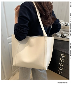 Detailed side view of a large cream leather tote bag styled on a female shoulder