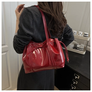 Detail view of red patent leather shoulder bag featuring bow knot and side drawstring