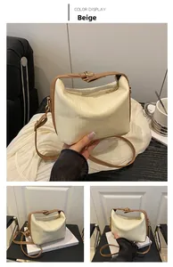Detailed view of beige striped leather handbag showing metal buckle and detachable shoulder strap