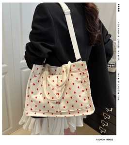 Detail of corduroy tote bag featuring red heart patterns and adjustable shoulder straps