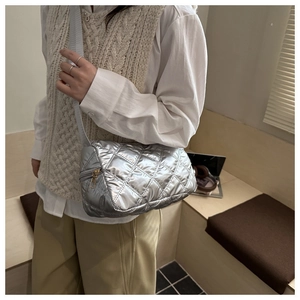 Close-up of a silver quilted puffer shoulder bag with a gray strap and golden zipper
