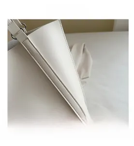 Detailed close-up of white leather tote bag with silver hardware and double stitching