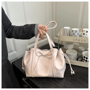 Pink patent leather dumpling shoulder bag with bow detail and adjustable drawstring