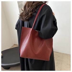Detail of burgundy embossed tote bag with woven texture worn by model for beach fashion